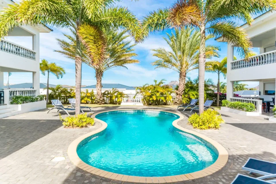 Turquoise zwembad met ligbedden tussen de Palm Crest-appartementen
